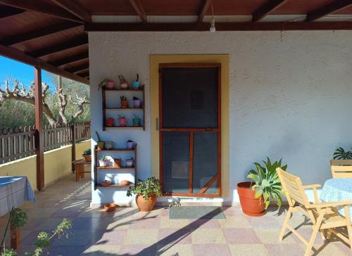 a patio with plants and a door on a house at Golden Horizon Retreat, 2 min walk from the sea! in Gournes