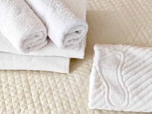 een stapel handdoeken bovenop een bed bij Like Home Guest Rooms in Alma-Ata