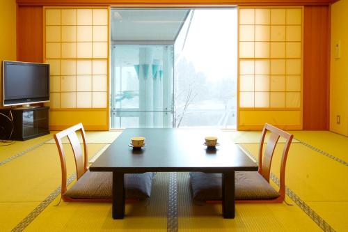 a dining room with a table and chairs and a tv at Hotel Symphony Annex Sagae Onsen in Sagae