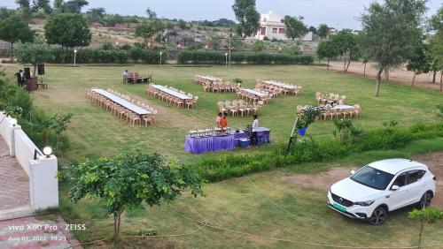 une voiture blanche garée dans un champ avec un groupe de tables dans l'établissement Shiva Green Valley Farms, à Bikaner