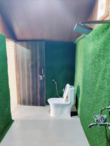a bathroom with a toilet and a green wall at Shiva Green Valley Farms in Bikaner