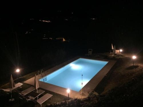 una gran piscina por la noche con sillas y luces en Appartement in Rignano Sull'arno mit Schöner Terrasse, en Rignano sullʼArno