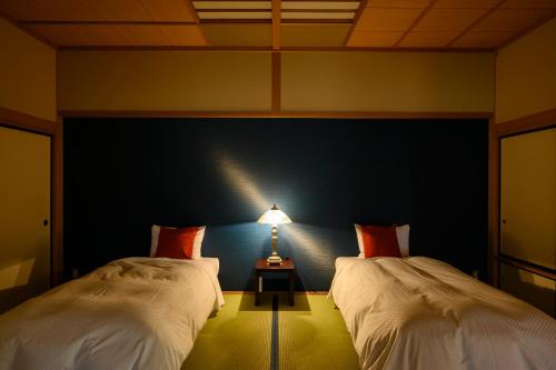 a bedroom with two beds and a table with a lamp at Hotel Symphony Annex Sagae Onsen in Sagae