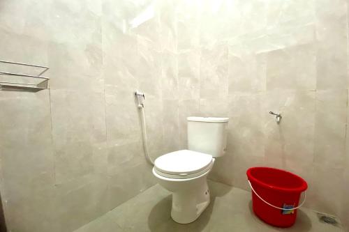 a bathroom with a toilet and a red bucket at OYO 93838 Delia Inn Syariah in Klaten