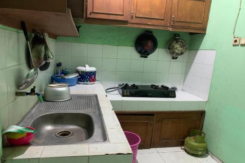 cocina con fregadero y fogones en OYO 93839 Aquenda Homestay en Yogyakarta