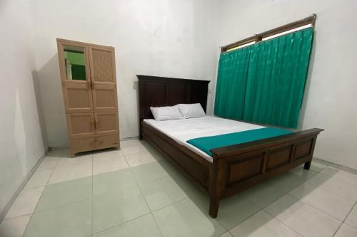 Habitación pequeña con cama y cortina verde en OYO 93839 Aquenda Homestay, en Yogyakarta
