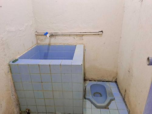 - une salle de bains avec des toilettes bleues dans une cabine dans l'établissement SPOT ON 93840 Guest House Amanda Syariah, à Bandar Lampung