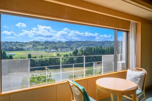 a room with a large window with a table and chairs at Hotel Symphony Annex Sagae Onsen in Sagae