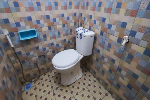 La salle de bains est pourvue de toilettes et d'un mur carrelé. dans l'établissement Capital O 93842 Jowo Segoro Resort, à Yogyakarta