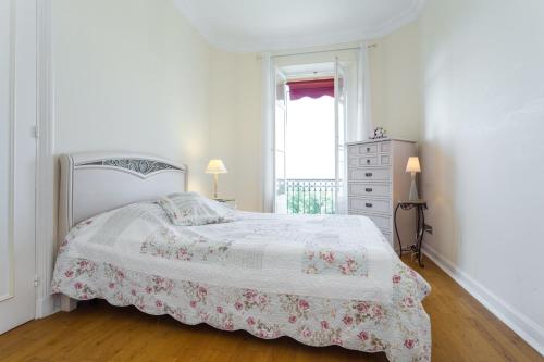 une chambre blanche avec un lit avec un couvre-lit fleuri dans l'établissement Appartement Claire Deluxe, à Cannes