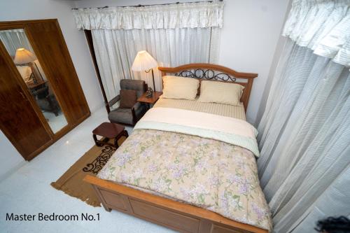 a bedroom with a bed and a chair and a mirror at Swarloke Apartment at Gulshan 2,Dhaka in Dhaka