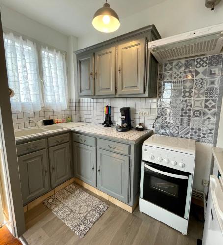 une cuisine avec des placards gris et des appareils blancs dans l'établissement Le Phare du Tréport - Vue Quai - Hyper Centre, au Tréport