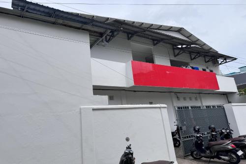 a white building with a red stripe on it at Hotel O Kost Reski 2 Near Tugu Perbatasan Takalar - Gowa in Rambia
