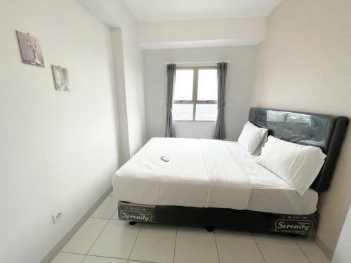 a bedroom with a bed in a room with a window at OYO 93857 Apartemen Kalibata City By Artomoro in Jakarta