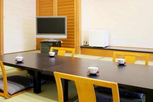 a conference room with a table and chairs and a tv at Hotel Symphony Annex Sagae Onsen in Sagae