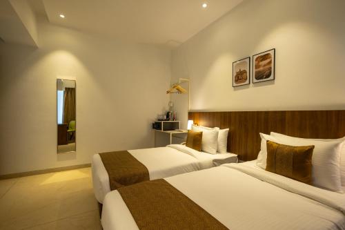 a hotel room with two beds and a mirror at Freesia Residency By Express Inn - Navi Mumbai in Navi Mumbai