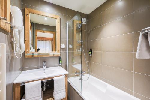 a bathroom with a sink and a tub and a mirror at Hôtel et Spa les Clarines in Corrençon-en-Vercors