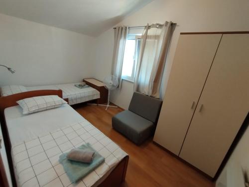 een kleine kamer met 2 bedden en een stoel bij Apartments Mali Dvori in Srima