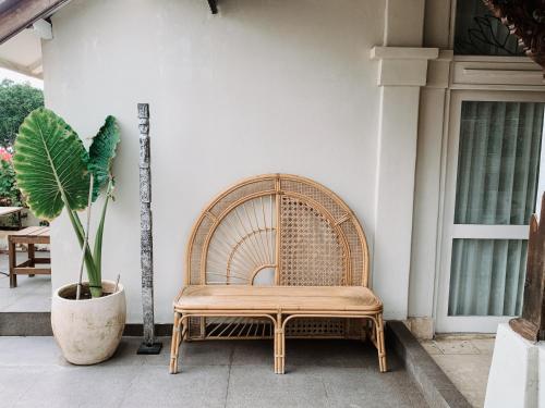 a wicker chair sitting on a porch next to a plant at Kresna By The Sea By Kresna Hospitality in Seminyak