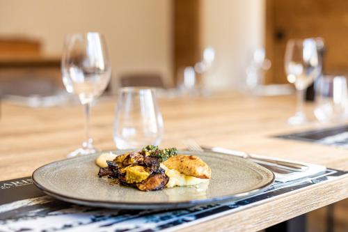 a plate of food on a table with wine glasses at Hôtel et Spa les Clarines in Corrençon-en-Vercors