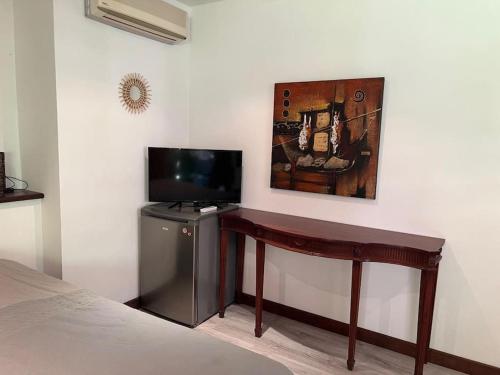 Habitación con escritorio y TV en la pared. en Bungalow Sarraméa en Sarraméa