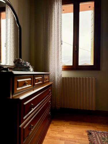 a bathroom with a dresser and a mirror and two windows at Casa Rosa in Teolo