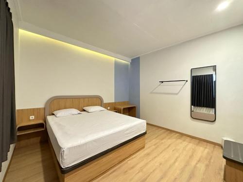 Dormitorio pequeño con cama y espejo en Hotel Plampitan, en Semarang