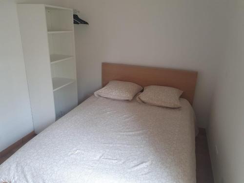 une petite chambre avec un lit avec deux oreillers dans l'établissement Maison plain pied avec jardin, à Villeneuve-le-Roi