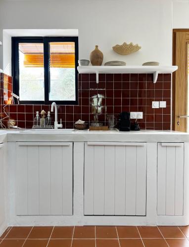 uma cozinha com armários brancos e um lavatório em Bergerie casitas suite em Canet-en-Roussillon