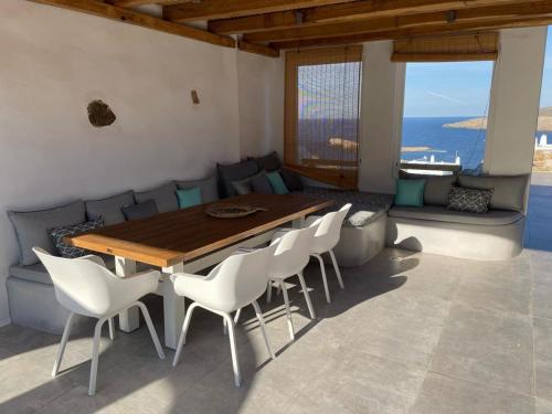 una sala da pranzo con tavolo in legno e sedie bianche di Mykonian 4 Bd Ocean Dream House in Agios Sostis ad Agios Sostis Mykonos