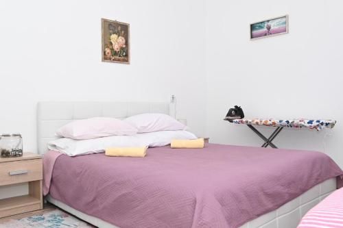 1 dormitorio con 1 cama con manta morada en Apartment Oscar en Mokošica