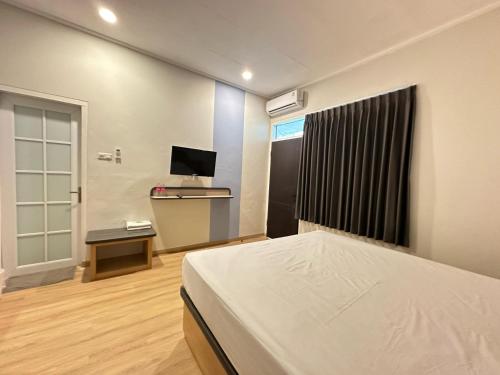 a bedroom with a bed and a desk and a television at Hotel Plampitan in Semarang