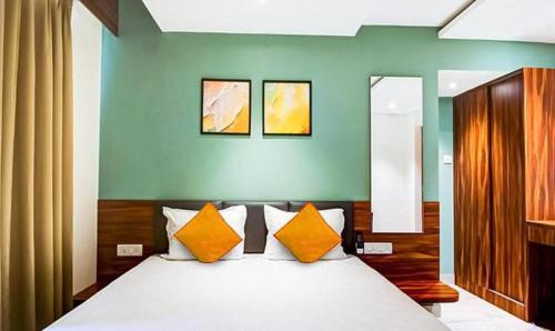 una camera da letto con un grande letto con cuscini arancioni di FabHotel Peak Stay ad Alto Porvorim