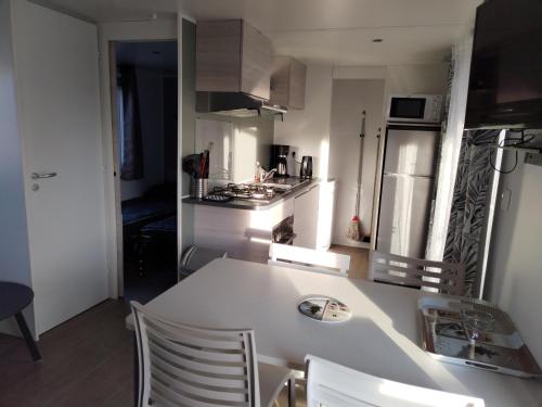 a kitchen with a white counter and chairs in it at Camping Le Lac des Rêves Lattes in Pérols