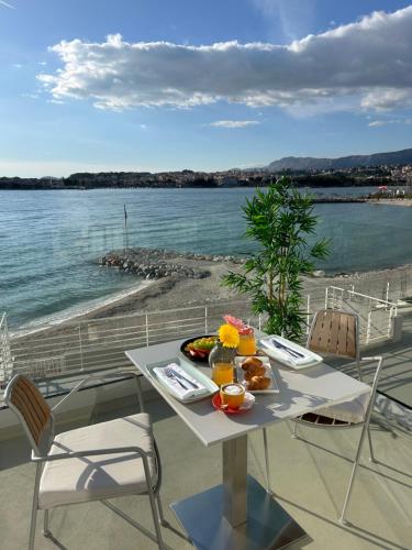 einen Tisch mit einem Teller Essen neben dem Wasser in der Unterkunft Hotel Split in Podstrana