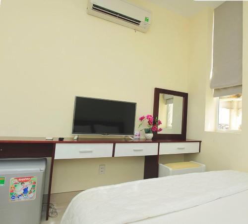 a bedroom with a television on a desk with a mirror at Khách sạn Minh Nhân in Vung Tau