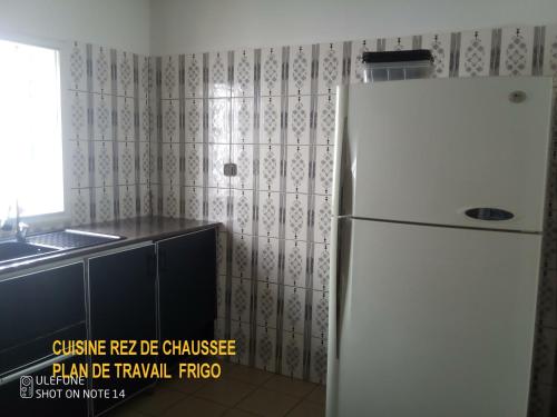 uma cozinha com um frigorífico branco e um lavatório em Hôtel LE CARRE D'AS MANDROSOA IVATO em Ivato