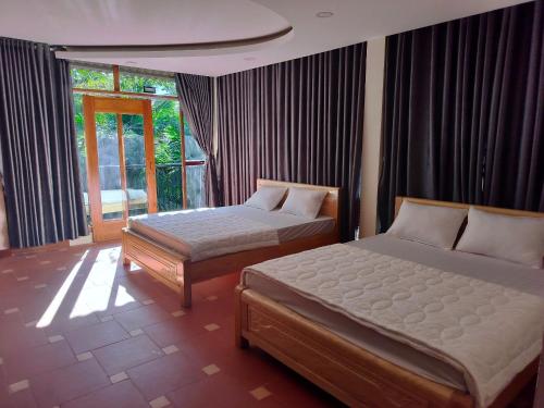 1 dormitorio con 2 camas y ventana en Khu du lịch Suối Ong, en Buôn Erang