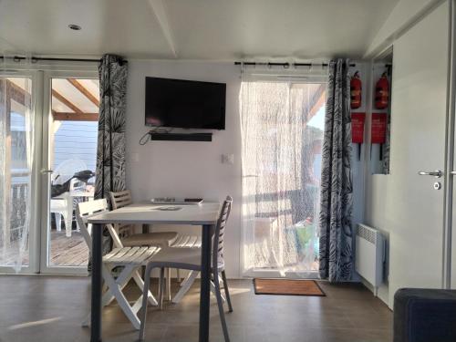 a dining room with a table and chairs and a television at Camping Le Lac des Rêves Lattes in Pérols