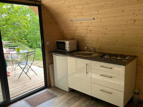 une cuisine avec un four micro-ondes et une table sur une terrasse dans l'établissement La Cabane enchantée, Mas Favières, à Notre-Dame-de-la-Rouvière