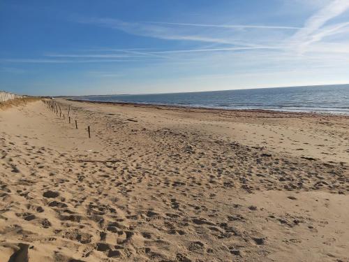 a beach with a fence in the sand and the ocean at Studio 2 à 4 personnes proche de la plage in La Guérinière