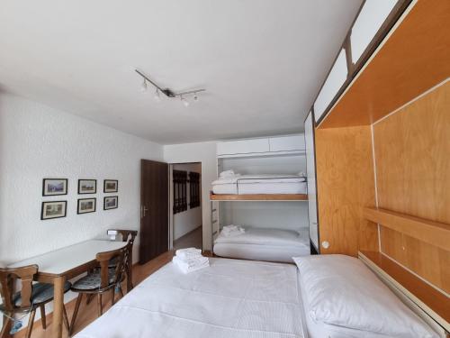 a bedroom with two beds and a desk and a table at Holiday flat for skiing couples Triangel D - Parpan Lenzerheide in Parpan