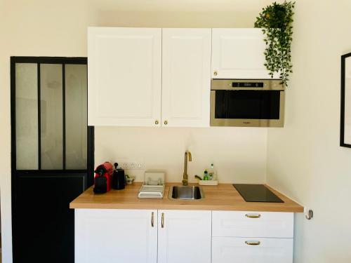 a kitchen with white cabinets and a sink at Studio de charme bien equipé - Matelas de qualité - Proche de la gare et de Versailles in Marly-le-Roi