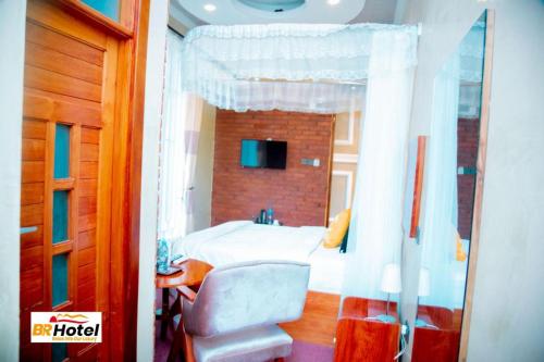 una camera con letto, sedia e specchio di BR HOTEL & APARTMENT a Dar es Salaam