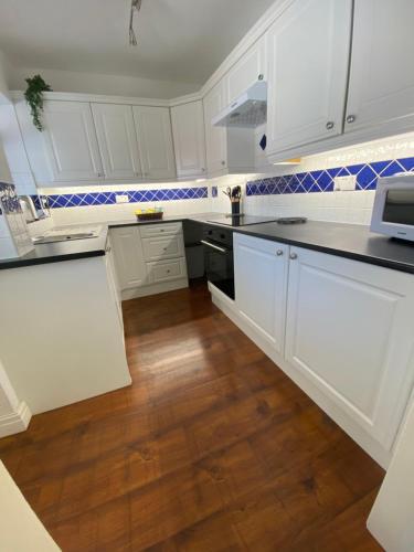 uma cozinha com armários brancos e bancadas pretas em Spacious 3 Bed House in Penrhyn Bay Llandudno em Llandudno