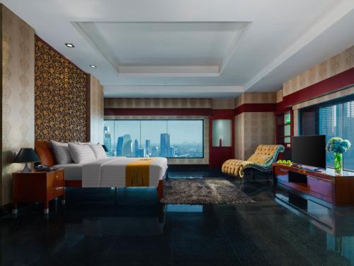 a bedroom with a bed and a desk and a television at Manhattan Hotel Jakarta in Jakarta