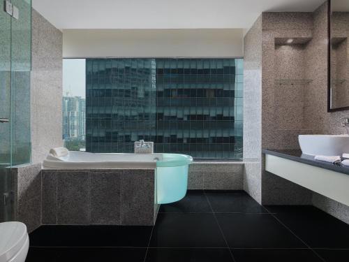 y baño con bañera, aseo y lavamanos. en Manhattan Hotel Jakarta, en Yakarta