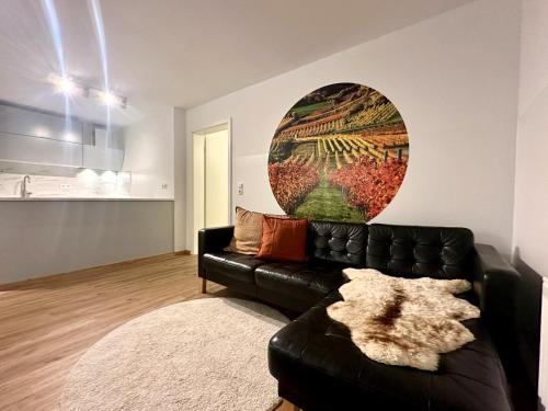 a living room with a black leather couch at SPEYERBACH - modernes Apartment nahe Neustadter Innenstadt in Neustadt an der Weinstraße
