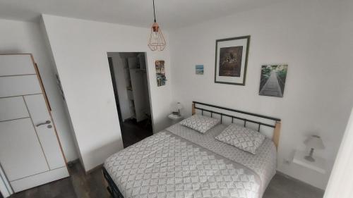 1 dormitorio con 1 cama con edredón blanco en La grenouillère, en Morcenx