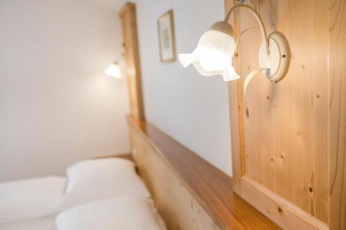 a room with a bed with a mirror and a lamp at Hotel & Residence Rebhof in Tirolo